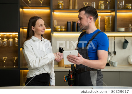 Foreman shows woman plan of kitchen renovation in tablet 86859617