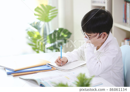 Student in a mask studying hard and concentrating and taking notes on books and notes Student in a mask studying hard and concentrating and taking notes on books and notes 86861134
