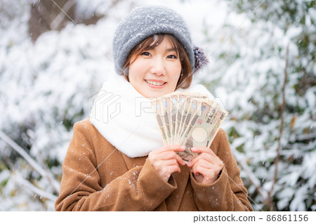 Female holding cash outdoors in winter Female holding cash outdoors in winter 86861156