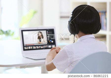 Boy concentrating on studying with teacher while taking online class on laptop at home wearing wireless headphones Boy concentrating on studying with teacher while taking online class on laptop at home wearing wireless headphones 86861221