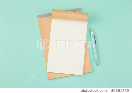 Open notepad with pen on green background 86861769