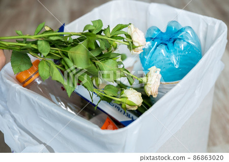 Withered white rose and other flowers in trash can. Dried flowers and leaves. Old flowers 86863020
