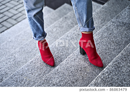 Woman legs in red sexy trendy stretch knitted fabric pointed toe block heel sock boots shoes and blue denim jeans pants Woman legs in red sexy trendy stretch knitted fabric pointed toe block heel sock boots shoes and blue denim jeans pants 86863479
