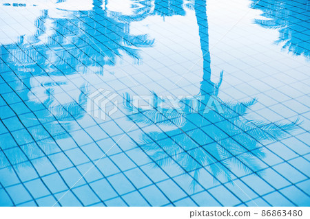Tropical background of palm trees leaves reflection in the blue calm water surface of a luxury hotel pool. Abstract background with openwork outline of palm leaves. Holiday vacation concept. 86863480