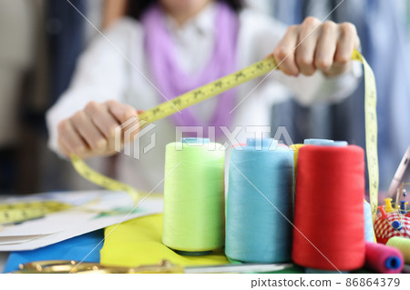 On the table of a seamstress are colored bobbins with threads 86864379