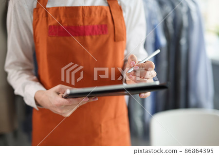 Woman dry cleaning administrator in an apron makes notes Woman dry cleaning administrator in an apron makes notes 86864395