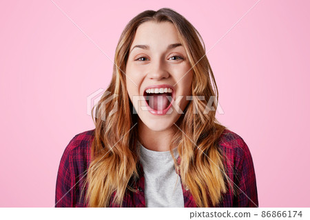 Studio shot of overjoyed happy female laughs at good joke, keeps mouth widely opened, being excited, isolated over pink studio background. Amazed beautiful woman expresse positiveness, poses in studio Studio shot of overjoyed happy female laughs at good joke, keeps mouth widely opened, being excited, isolated over pink studio background. Amazed beautiful woman expresse positiveness, poses in studio 86866174