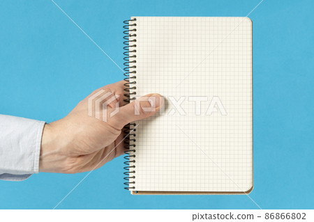 Man hand holding a notebook with square grid Man hand holding a notebook with square grid 86866802