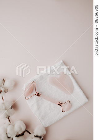 Skin care concept. Massage tools for face therapy with towel on a pink background. Vertical image Skin care concept. Massage tools for face therapy with towel on a pink background. Vertical image 86866909