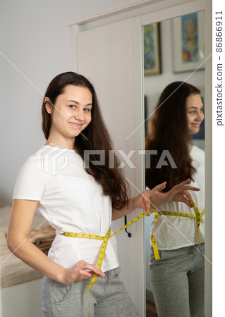 Portrait of woman taking measurements of waist Portrait of woman taking measurements of waist 86866911