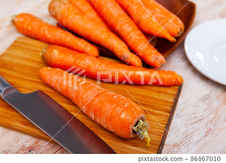 Raw unpeeled carrots on wooden table 86867010