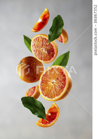 Bloody orange levitation. Oranges slices in the aer with green leaves. Abstract citrus fruit composition. 86867352