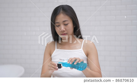 Daily routine concept. Young Asian woman gargling in the bathroom. 4k Resolution. Daily routine concept. Young Asian woman gargling in the bathroom. 4k Resolution. 86870610