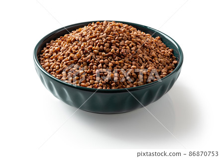 Raw wholegrain buckwheat groats in a blue bowl isolated on a white background. Raw wholegrain buckwheat groats in a blue bowl isolated on a white background. 86870753