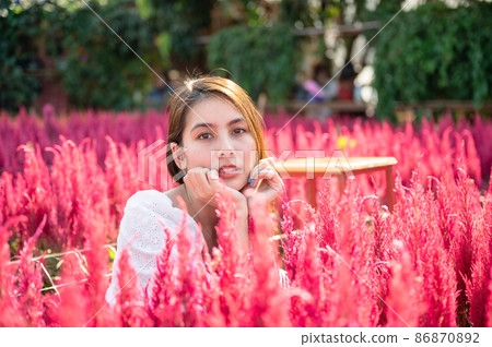 Beautiful young asian woman sitting in cockscomb flower garden 86870892