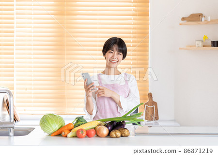 操作智能手機的一個少婦在廚房裡 86871219