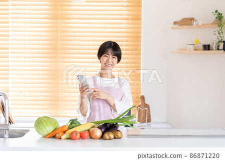 操作智能手機的一個少婦在廚房裡 86871220