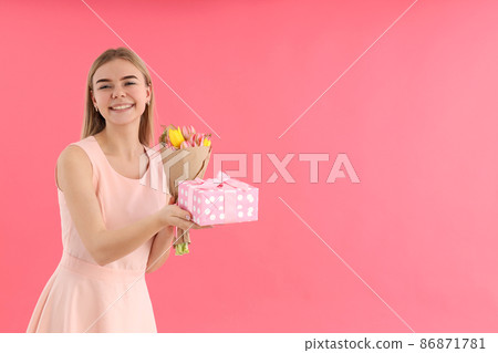 Young woman with bouquet and gift box on pink background 86871781