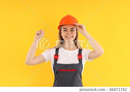 Builder woman on yellow background, equality concept Builder woman on yellow background, equality concept 86871782