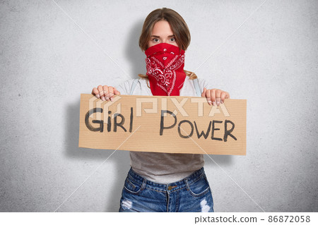 Active powerful cute young female looking directly at camera, showing inscription girl power, curious about social problems, uniting like minded people, isolated over grey background in studio. Active powerful cute young female looking directly at camera, showing inscription girl power, curious about social problems, uniting like minded people, isolated over grey background in studio. 86872058