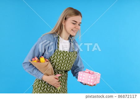 Housewife with bouquet and gift box on blue background Housewife with bouquet and gift box on blue background 86872117