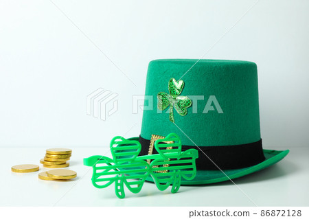 Top hat, chocolate coins and clover leaf glasses on white table 86872128