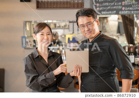 Male and female clerk consulting with a tablet PC at a restaurant 86872910