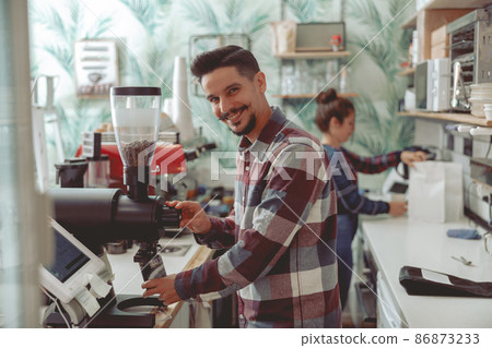 Man barista working in coffee shop near coffee grinder 86873233