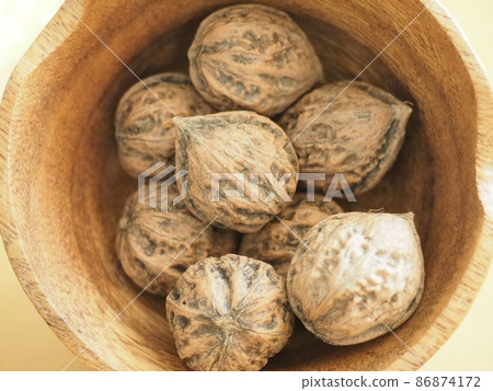 Walnuts with shells in a wooden bowl Walnuts with shells in a wooden bowl 86874172