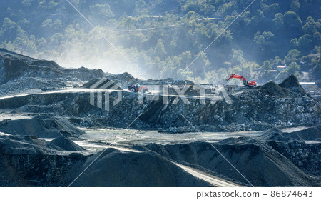 Piles of crushed stone and mining machinery working at diabase quarry 86874643