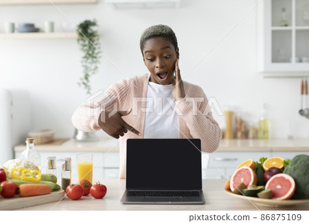 Shocked millennial african american lady with open mouth point finger at laptop with blank screen 86875109