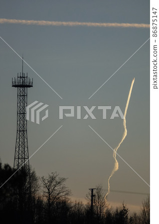 Air plane traces on the sunset sky. Tree silhouettes background Air plane traces on the sunset sky. Tree silhouettes background 86875147