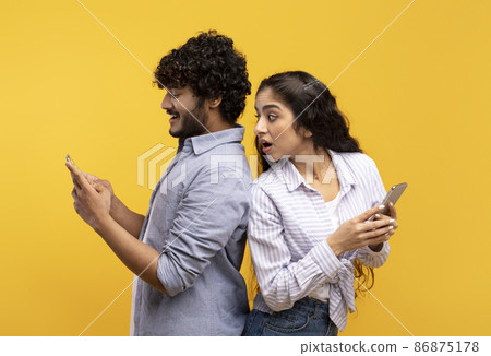Shocked indian woman spying on her smiling boyfriend who using smartphone, chatting or scrolling social media feed Shocked indian woman spying on her smiling boyfriend who using smartphone, chatting or scrolling social media feed 86875178