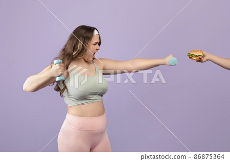 Confident millennial european plus size female in sportswear, exercising with dumbbells, scream and refusing burger Confident millennial european plus size female in sportswear, exercising with dumbbells, scream and refusing burger 86875364