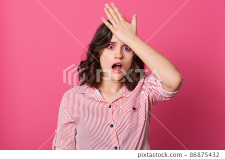 Indoor shot of frustrated forgetful young woman looking at camera with worried facial expression, holding hand on head, female realizes she forgot about doing something important. People concept. 86875432