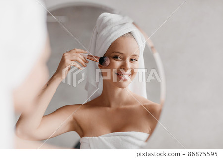 Happy lady getting ready for work, doing morning routine nude makeup, putting blush in bathroom at home 86875595