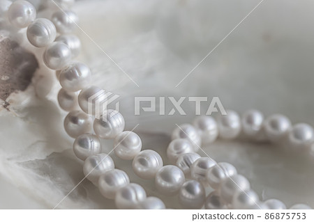 Nature white string of pearls on marble background in soft focus, with highlights. Nature white string of pearls on marble background in soft focus, with highlights. 86875753