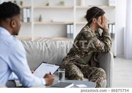 Upset man in camouflage crying while having conversation with psychologist 86875754