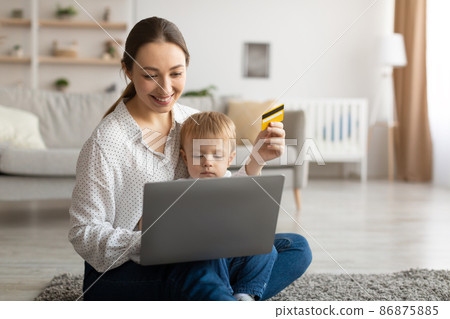 Easy payments. Happy young mother and her child with laptop and credit card purchasing together online, free space Easy payments. Happy young mother and her child with laptop and credit card purchasing together online, free space 86875885