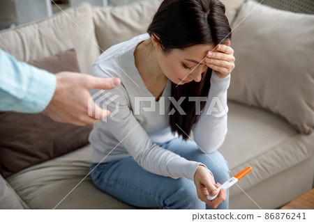 A sad young woman holds a pregnancy test in her hand. The concept of unwanted pregnancy. 86876241