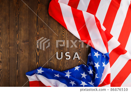 the word USA laid with silver metal letters on wooden board surface under crumpled flag of United States of America the word USA laid with silver metal letters on wooden board surface under crumpled flag of United States of America 86876510