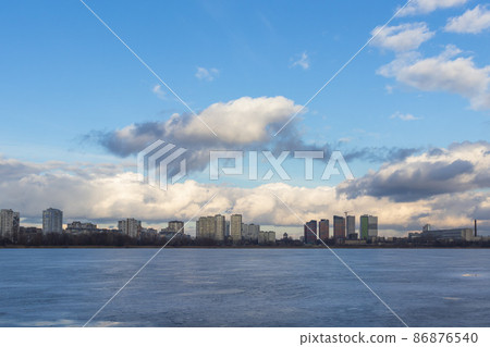 Urban winter landscape from frozen lake. Waste processing plant behind lake Urban winter landscape from frozen lake. Waste processing plant behind lake 86876540