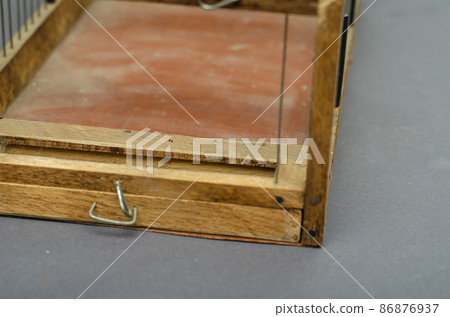 Close-up of an open wooden birdcage against a gray background. Handmade empty cage. Close-up. Selective focus. Close-up of an open wooden birdcage against a gray background. Handmade empty cage. Close-up. Selective focus. 86876937