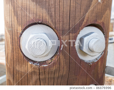 Screwed wood beams. Poles connected by metal screw and nut 86876996