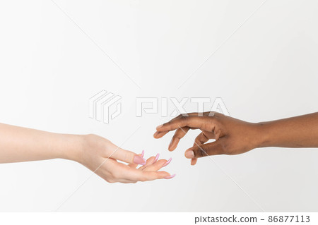 A helping hand outstretched to give support. Two hands approaching each other. Hands of two races, African and European, attracting each other. A helping hand outstretched to give support. Two hands approaching each other. Hands of two races, African and European, attracting each other. 86877113