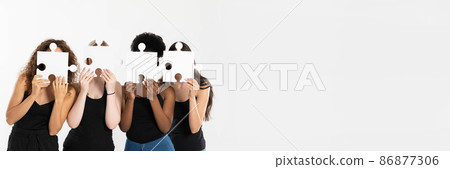 In a panoramic frame, four young girls hold puzzles in their hands, covering their face to become anonymous and show that differences connect, not divide. 86877306
