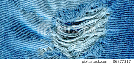 Hole and threads on denim jeans 86877317