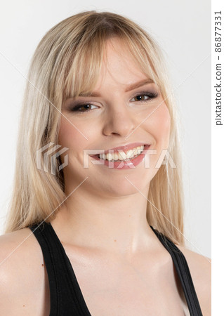 A young girl with a very fair complexion and long fair hair smiles sincerely. Portrait of a thoroughbred blonde from Eastern Europe. 86877331