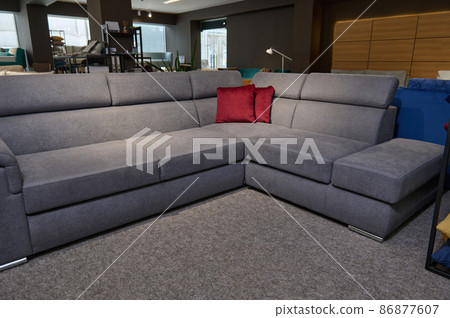 Upholstered furniture on display for sale in the showroom of furniture store. Modern stylish sofas, couches and settees with bright colored cushions from high quality fabrics in the exhibition hall. 86877607