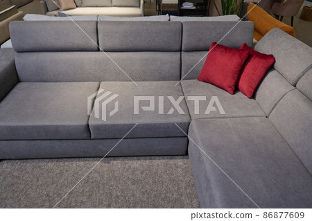 Upholstered furniture on display for sale in the showroom of furniture store. Modern stylish sofas, couches and settees with bright colored cushions from high quality fabrics in the exhibition hall. 86877609